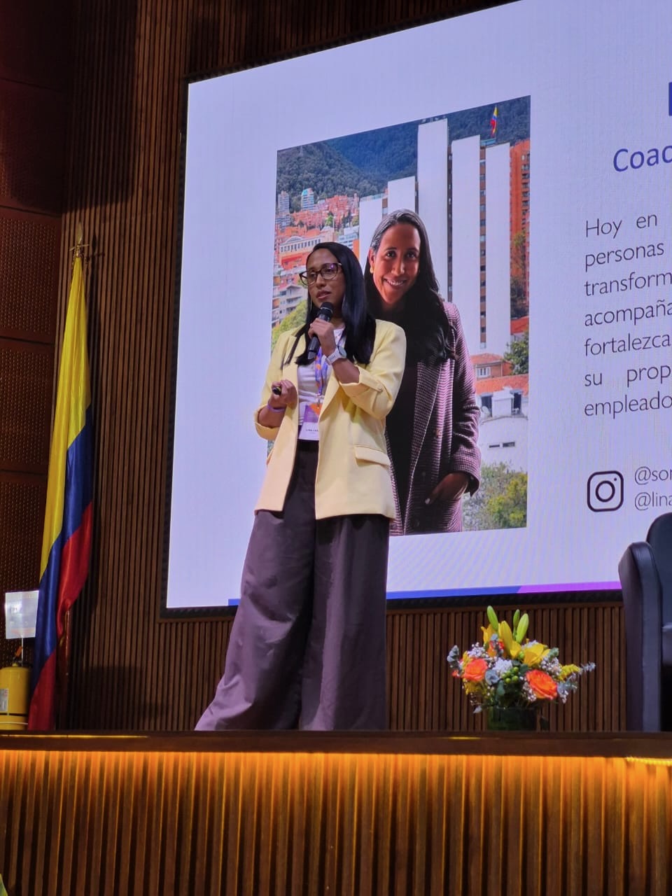 Lina Lasso hablando con un micrófono en un congreso, de blazer amarillo